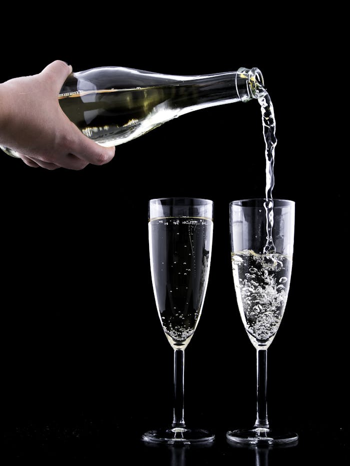 Elegant champagne being poured into two flutes against a black background, highlighting celebration and luxury.