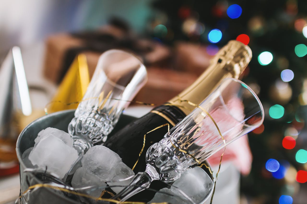 Close-up of champagne bottle and glasses in ice bucket, perfect for holiday festivities.